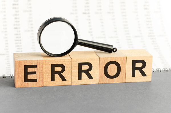 Wooden Blocks с текстом: Ошибка с лупой. Ошибочное слово, сделанное из строительных блоков. Концепция бизнеса