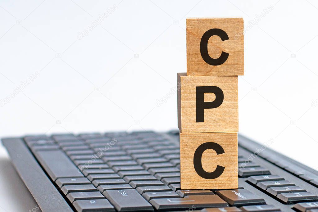 CPC - Cost Per Click - sign on a worn wooden table with a blurry background in bright colors. Concept image a wooden block and letters - CPC on white background. The cubes are located on the keyboard