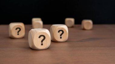Açık siyah zemin üzerinde soru işaretleri olan üç tahta küp fotokopi alanı, çözülme