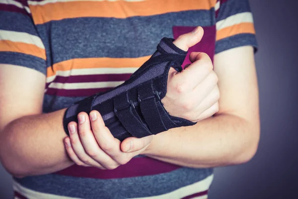 Человек с рукой в ортопедическом черном ортезе — стоковое фото
