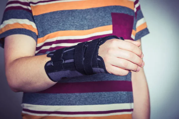 Homem com a mão em órtese preta ortopédica — Fotografia de Stock