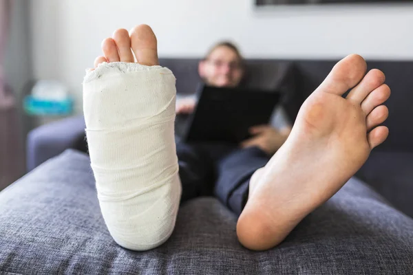 Muž sedí doma se zlomenou nohou — Stock fotografie
