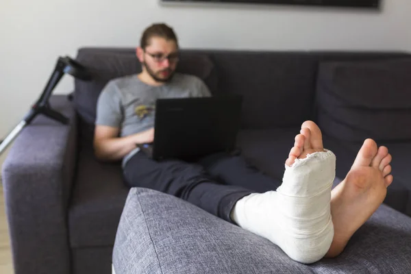 Muž se zlomenou nohou je surfování na internetu — Stock fotografie
