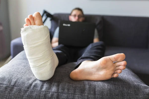 Homem com uma perna quebrada está navegando na internet — Fotografia de Stock