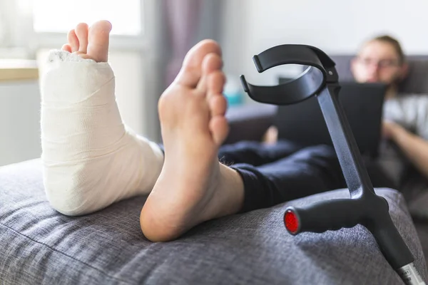 Man with a sprained ankle sitting on a sofa at home — Stock Photo, Image