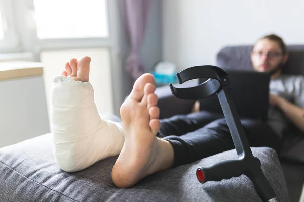 Garçon avec des béquilles et jambe cassée à la maison — Photo