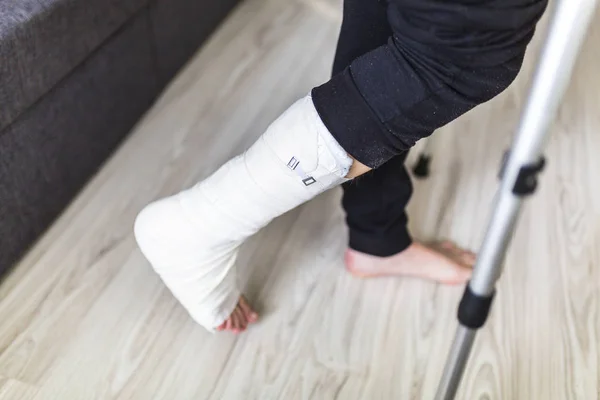 Caminar sobre muletas con una pierna en un yeso — Foto de Stock