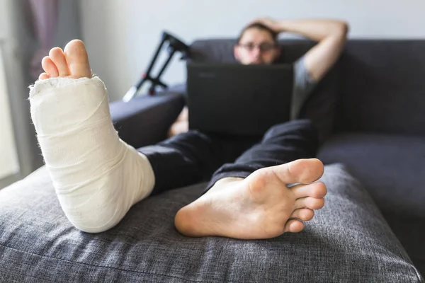 Homem com uma perna quebrada está navegando na internet — Fotografia de Stock