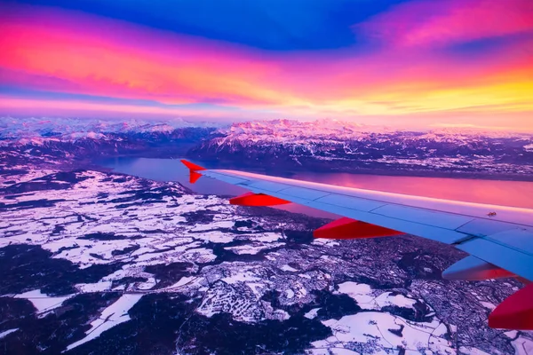 Increíble vista desde la ventana del avión durante la puesta de sol sobre las montañas en Suiza — Foto de Stock