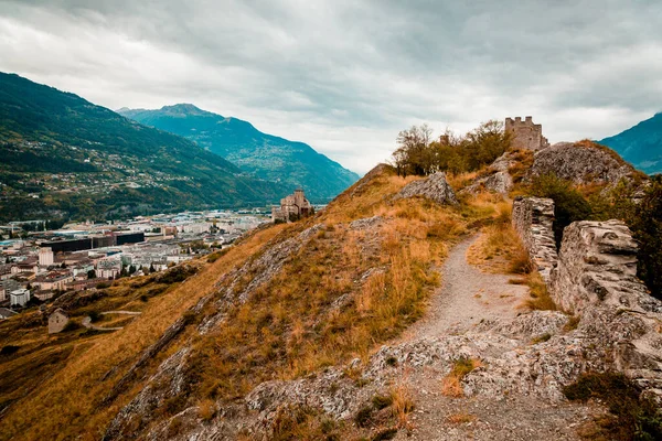 Sion, Suiza: Ruinas del castillo de Tourbillon situado en una colina con la basílica de Valere en un fondo —  Fotos de Stock