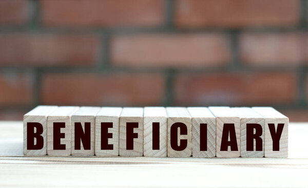 concept word BENEFICIARY on cubes against the background of a brick wall