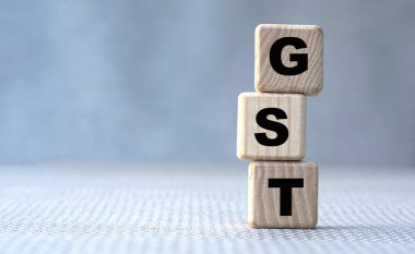 konsept kelime GST (Mal ve Hizmetler Vergisi) gri arka planda tahta küplerin üzerinde. İş konsepti