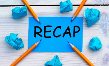 RECAP - Kırışmış kağıt ve kalemlerle birlikte açık arkaplan üzerine mavi kağıt üzerinde kelime.
