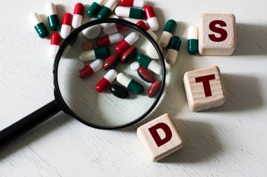 STD (cinsel yolla bulaşan hastalıklar) - büyüteç ve tabletlerle hafif arkaplan üzerindeki küplerle ilgili bir kelime. Tıbbi konsept