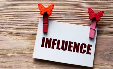 INFUENCE - beyaz bir çarşaf üzerinde kelime ahşap bir arka planda güzel mandallar. Teknoloji ve eğitim kavramı