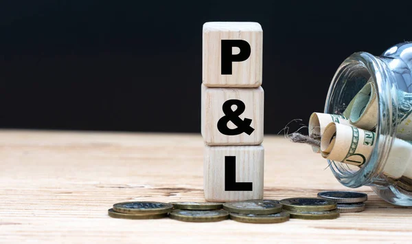 P&L(Profit and Loss) - on cubes on the background of a capacity with money. Business and finance.