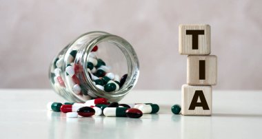 TIA (Geçici İskemik Saldırı) - tabletlerle birlikte hafif arkaplandaki küplerin kısaltması. Tıbbi konsept.