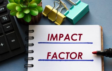 IMPACT FACTOR kelimeleri bir deftere işaretleyici, hesap makinesi, kıskaç ve kaktüs ile yazılır. İş konsepti