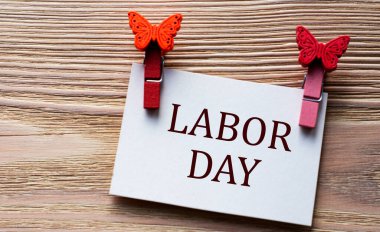 LABOR GÜNÜ - Beyaz bir çarşaf üzerinde kelime ahşap bir arka planda güzel mandallar ile. Teknoloji ve eğitim kavramı