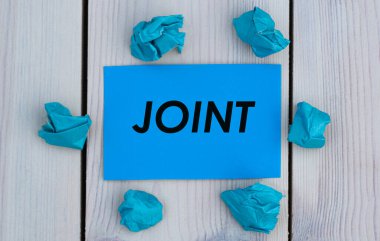 JOINT - Kırışmış kağıt parçalarıyla açık arkaplan üzerine mavi kağıt üzerinde kelime