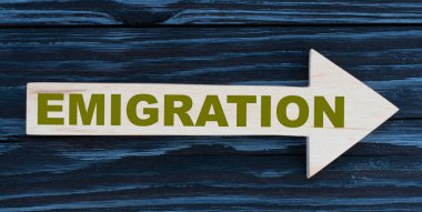 Göçmenlik kelimesi güzel, karanlık bir arkaplanda tahta bir okun üzerine yazılmış.