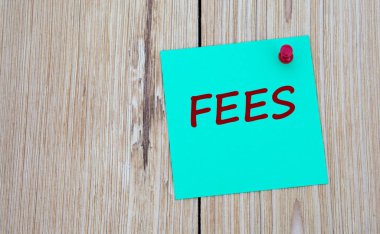 Ücret - notlar için yeşil bir sayfaya yazılmış kelime, ki bu da tahta bir tahtaya iğnelenmiş. İş konsepti