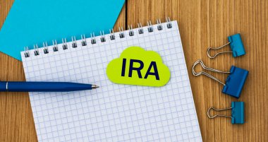 Ira, tahta arka planda bir deftere kalem ve kıskaçla yazılmış bir kelime. İş konsepti