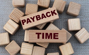 PAYBACK TIME - words on wooden bars on cubes on a gray background. Business and finance concept clipart