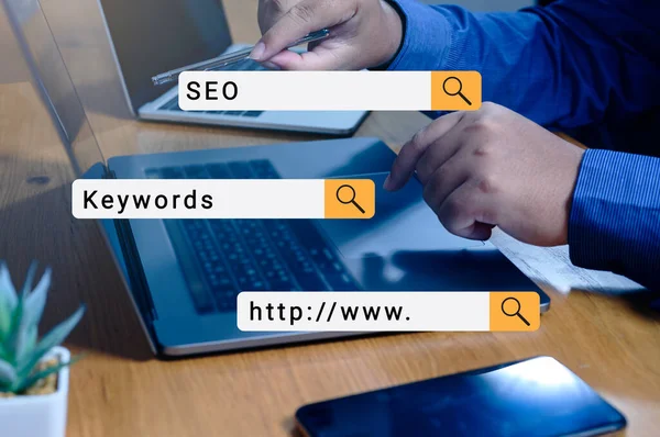 İnternette iş adamı eliyle bilgisayar kullanarak arama yapmak arama motoru çubuğu ile. seo kavramları, anahtar kelimeler ve www.