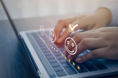 İş kadını klavye bilgisayarında yüz ifadesine basıyor. Müşteri hizmetleri değerlendirmesi ve araştırma konsepti.