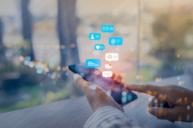 Cep telefonunda sosyal medya pazarlama kavramını kullanan kadın eli, uyarı simgeleri, mesaj, yorum ve cep telefonu ekranının üstündeki yıldız gibi.