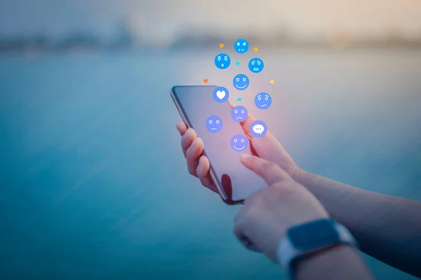 Person using a social media marketing concept on mobile phone with notification icons of like, message, comment and star above smartphone screen.