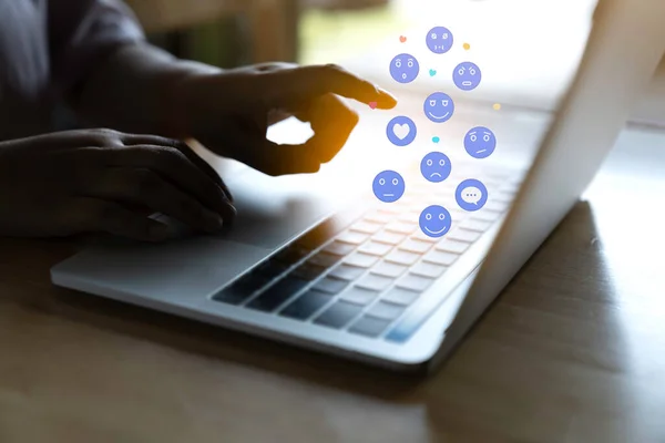 Person using a social media marketing concept on laptop computer with notification icons of like, chat, message and comment above laptop keyboard.
