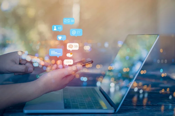 Woman hand using a social media marketing concept on mobile phone with notification icons of like, message, comment and star above mobile phone screen.