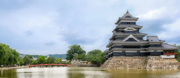 Matsumoto Castle is located in middle of water with red bridge to cross castle, which one of the historical sites in Japan. present it is a park and tourist attraction that has many tourists visiting.