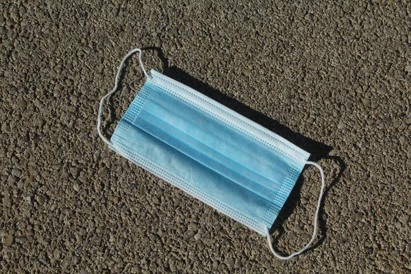 Bir yola atılmış virüs koruma maskesi.