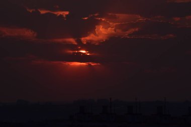 Karşıt gökyüzü, uzaktaki bir metropolün arka planında parlak bir günbatımıdır. Ufuk çizgisi çok büyülü ve heyecan vericidir. Bu bir kıyamettir.