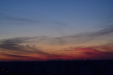 Karşıt gökyüzü, uzaktaki bir metropolün arka planında parlak bir günbatımıdır. Ufuk çizgisi çok büyülü ve heyecan vericidir. Bu bir kıyamettir.