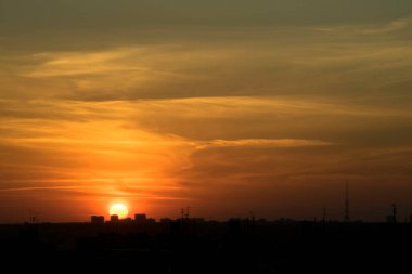 Karşıt gökyüzü, uzaktaki bir metropolün arka planında parlak bir günbatımıdır. Ufuk çizgisi çok büyülü ve heyecan vericidir. Bu bir kıyamettir.