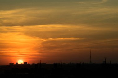 Karşıt gökyüzü, uzaktaki bir metropolün arka planında parlak bir günbatımıdır. Ufuk çizgisi çok büyülü ve heyecan vericidir. Bu bir kıyamettir.