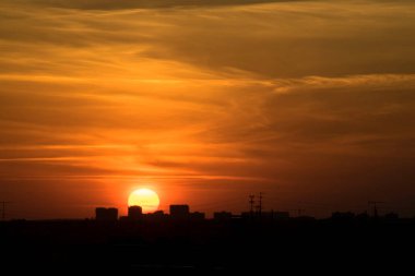 Karşıt gökyüzü, uzaktaki bir metropolün arka planında parlak bir günbatımıdır. Ufuk çizgisi çok büyülü ve heyecan vericidir. Bu bir kıyamettir.