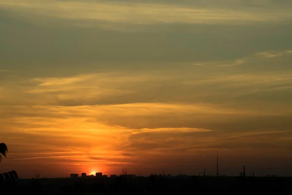 夕日の明るいコントラストで家の上の大都市のスカイラインの上に夕日 明るい 見事な雲の中の地平線に信じられないほどの太陽 合格日の見事な魅力的な写真 — ストック写真