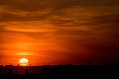 Karşıt gökyüzü, uzaktaki bir metropolün arka planında parlak bir günbatımıdır. Ufuk çizgisi çok büyülü ve heyecan vericidir. Bu bir kıyamettir.