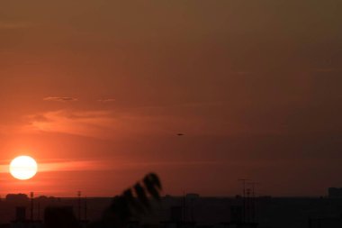 Ukrayna 'nın büyük bir şehri, Harkiv şehrinin üzerinde zıt bir günbatımında kırmızı bir gökyüzü ve güneş ufukta kaybolacak, geçen günün çarpıcı görüntüsü ve gece ile gündüz buluşması. Ufuktaki bulutlar