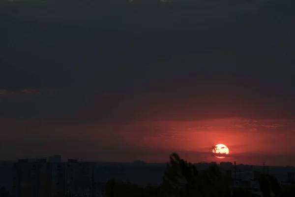 ウクライナの大都市の上に対照的な日没で真紅の空 最後の数秒でハリコフ市と太陽は地平線の後ろに消えます 通過日の素晴らしい景色と日と夜の会議 地平線の雲 — ストック写真