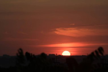 Ukrayna 'nın büyük bir şehri, Harkiv şehrinin üzerinde zıt bir günbatımında kırmızı bir gökyüzü ve güneş ufukta kaybolacak, geçen günün çarpıcı görüntüsü ve gece ile gündüz buluşması. Ufuktaki bulutlar