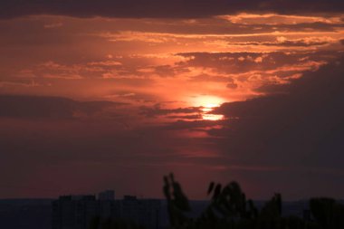 Ukrayna 'nın büyük bir şehri, Harkiv şehrinin üzerinde zıt bir günbatımında kırmızı bir gökyüzü ve güneş ufukta kaybolacak, geçen günün çarpıcı görüntüsü ve gece ile gündüz buluşması. Ufuktaki bulutlar