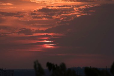 Ukrayna 'nın büyük bir şehri, Harkiv şehrinin üzerinde zıt bir günbatımında kırmızı bir gökyüzü ve güneş ufukta kaybolacak, geçen günün çarpıcı görüntüsü ve gece ile gündüz buluşması. Ufuktaki bulutlar