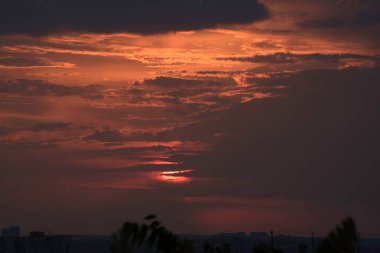 Ukrayna 'nın büyük bir şehri, Harkiv şehrinin üzerinde zıt bir günbatımında kırmızı bir gökyüzü ve güneş ufukta kaybolacak, geçen günün çarpıcı görüntüsü ve gece ile gündüz buluşması. Ufuktaki bulutlar