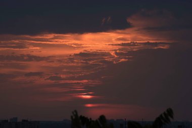 Ukrayna 'nın büyük bir şehri, Harkiv şehrinin üzerinde zıt bir günbatımında kırmızı bir gökyüzü ve güneş ufukta kaybolacak, geçen günün çarpıcı görüntüsü ve gece ile gündüz buluşması. Ufuktaki bulutlar